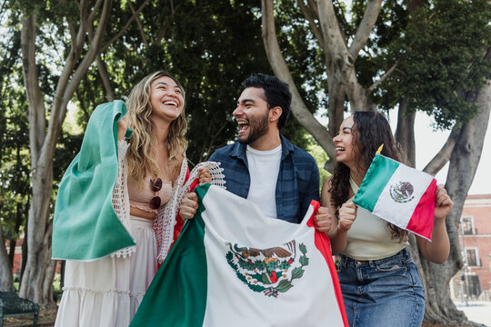 young Mexican people with flags to celebrate mexican independence day and cheering Viva Mexico