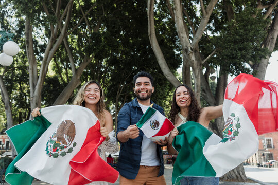 young Mexican people with flags to celebrate mexican independence day and cheering Viva Mexico