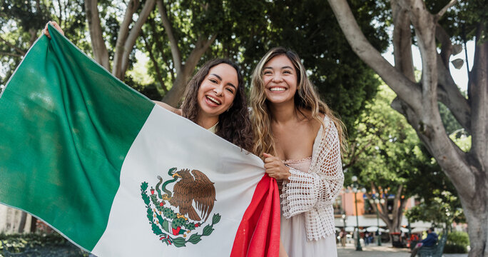young Mexican women friends with flags to celebrate mexican independence day and cheering Viva Mexico 