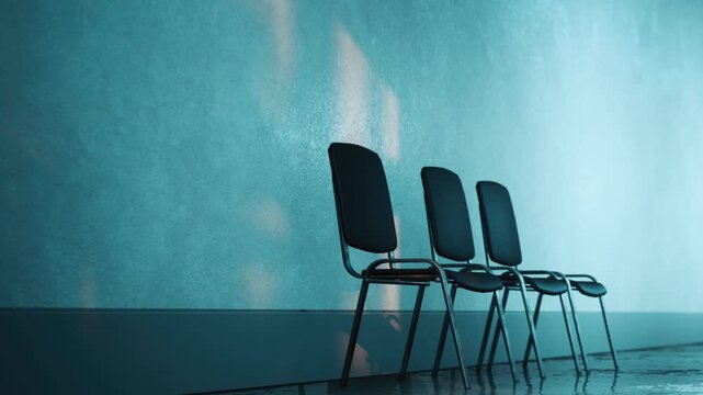 Three chairs are arranged in a row against a light blue wall. Sunlight shines through the windows, casting shadows on the floor. The setting is simple and bright.