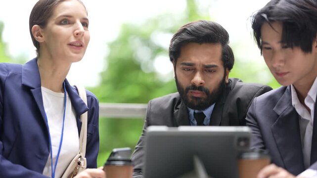 Three business colleagues work through a tablet report while drinking takeaway coffee on the open terrace of a modern corporate campus in the city centre, in an Asian metropolis