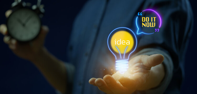 Businessman holding vintage alarm clock while open hand supporting glowing Idea lightbulb and Do It Now quote. Urgent creative execution, time management, and proactive business drive concept.