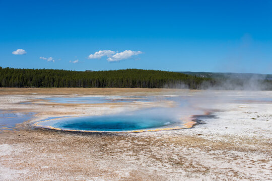 Celestine Pool hot springs in the midway geyser basin on a sunny blue sky day, summer vacation at Yellowstone National Park viewing natural geothermal features
