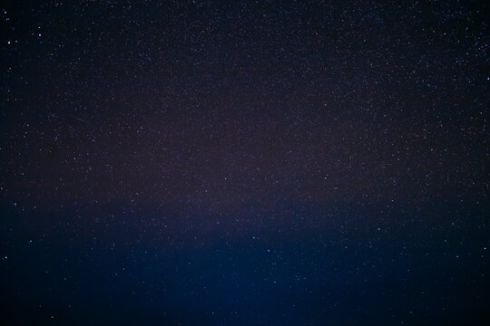 Vibrant purple and black starry night sky texture with constellations.