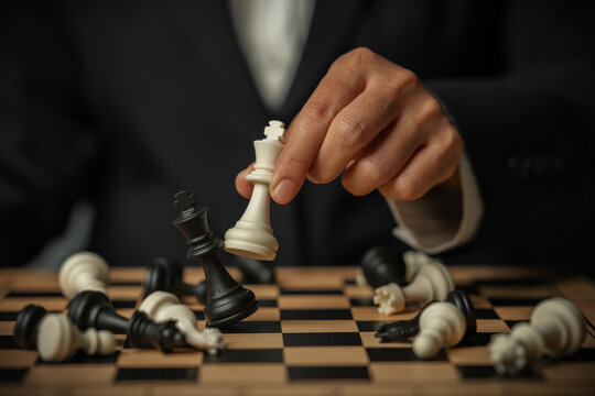 business hand holding white chess king taking black king, win and game over