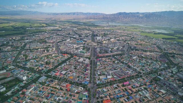 High-Angle Aerial Panoramic View of Tekes Bagua City in Ili: Unique Bagua I-Ching Geometric Layout, Radial Streets, Circular Ring Roads, Blue Sky and Mountain Range in Xinjiang