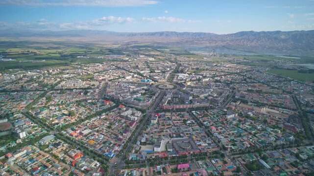 High-Angle Aerial Panoramic View of Tekes Bagua City in Ili: Unique Bagua I-Ching Geometric Layout, Radial Streets, Circular Ring Roads, Blue Sky and Mountain Range in Xinjiang