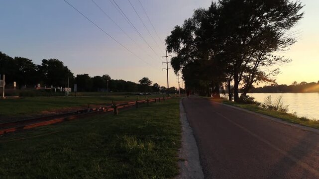 Panning right to left showing river water and a bike path during sunset. 