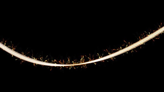 Sparkling glowing fuse wire burning on black background creating bright cinematic trail of golden sparks for festive climax.
