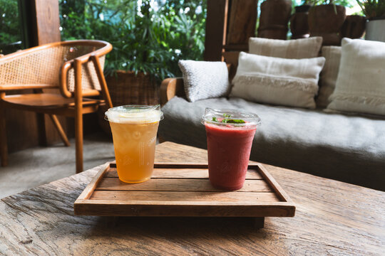 Iced lemon tea and refreshing fruit smoothie on a wooden tray in a cozy cafe setting