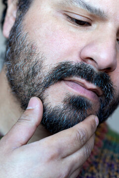 Macro shot of adult man inspecting his facial hair and skin texture after beard care routine