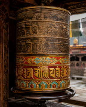 An ancient Tibetan prayer wheel in motion, patterns worn and vivid.