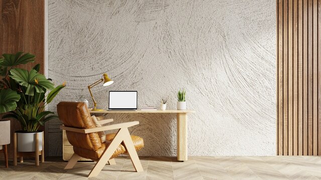 Modern home office workspace interior design with blank screen laptop on wooden desk, brown leather armchair, and green plant against textured white wall- 3D rendering