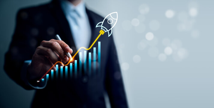 Startup business growth concept with professional using stylus on rising bar chart and rocket icon showing performance acceleration, revenue increase and success strategy