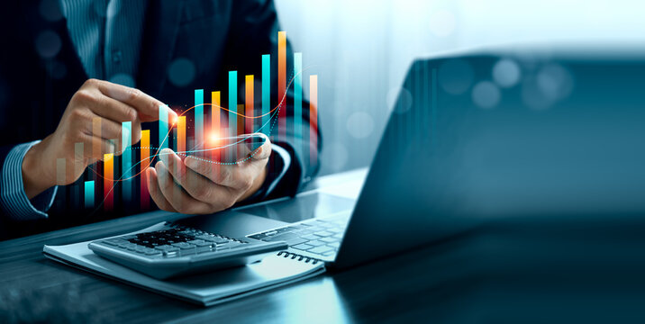 Financial data analytics concept with business professional using smartphone beside laptop and calculator showing digital bar chart forecast performance and investment growth