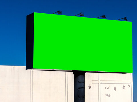 Large blank billboard with chroma key green screen structure on a metal pole under a clear blue sky, ideal for outdoor advertising mockup, commercial marketing template, and media message display