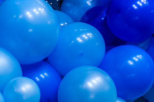 A close-up, full frame shot of multiple shades of glossy blue balloons clustered together, creating a festive backdrop. 