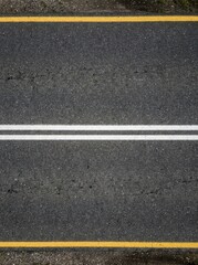Fototapeta premium Top View of Dark Asphalt Road Surface with Double White Center Lines and Yellow Edge Markings