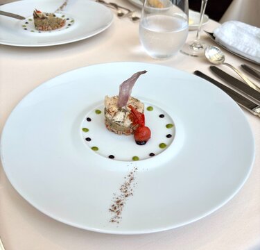 Gourmet appetizer with conger eel, eggplant and tomato served on white plate in fine dining restaurant