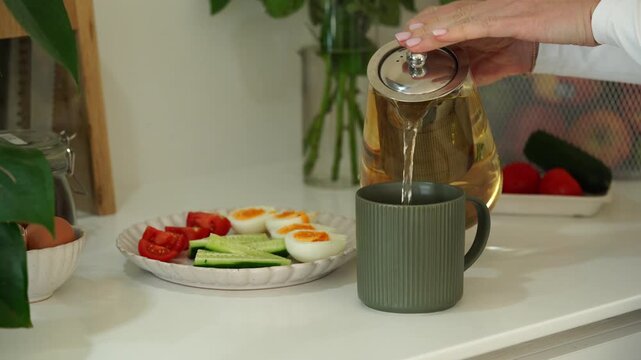Morning tea ritual: pouring fresh brewed tea with breakfast setup