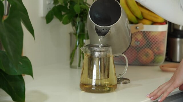 Pouring fresh tea: handless teapot with fruit and leaf background in modern kitchen setting