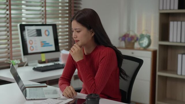 Stressed asian businesswoman experiencing headache at work