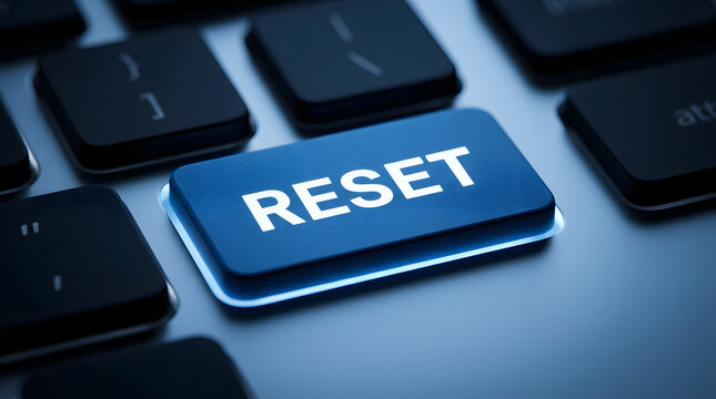 Close-up of a blue reset button on a metallic computer keyboard with black keys, featuring the word RESET in white capital letters, sharply focused with a shallow depth of field featuring blue button