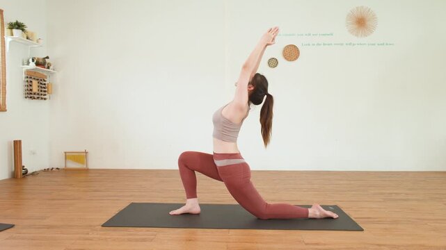 Asian Woman Performing Low Lunge Yoga Pose in Bright Studio
