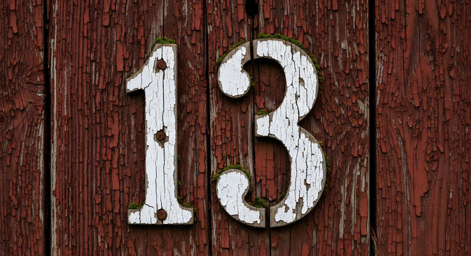 Number thirteen sign on old red wooden planks