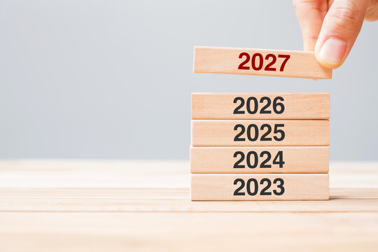 2027 block over 2026 and 2025 wooden building on table background. Business planning, Risk Management, Resolution, strategy, solution, goal, New Year New You and happy holiday concepts