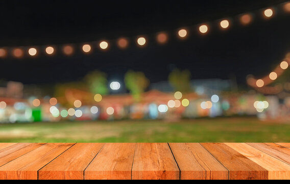 Empty wooden table top with blurred festive bokeh lights at night market