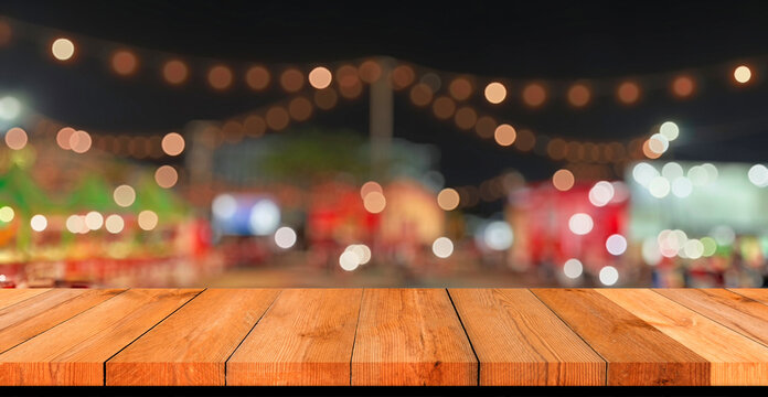 Empty wooden table top with blurred festive bokeh lights at night market