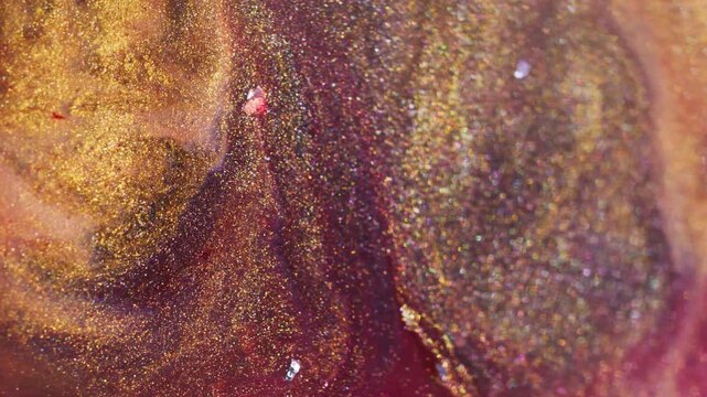 Shiny ink. Shimmer emulsion. Defocused yellow red purple color spatter glitter liquid crystal floating on abstract light background.