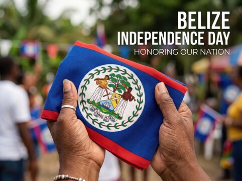 Hands holding a folded belize flag with the national coat of arms emblem during an outdoor independence day celebration with blurred people in the background