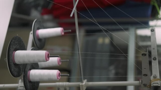 Vertical video. Thread spool factory. Textile studio equipment. White string unwound from bobbin sewing process in tailoring workplace.