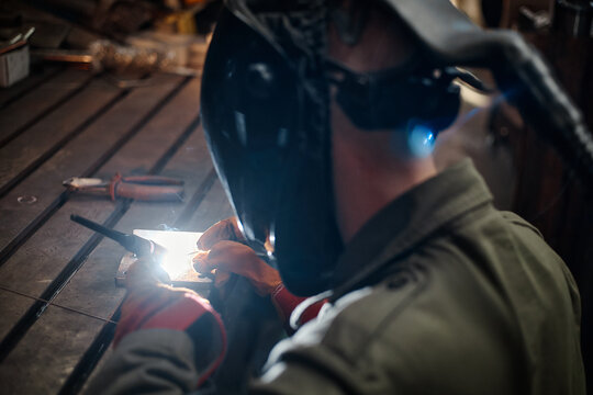 Caucasian young adult welder working together in metal fabrication workshop, focusing on precision welding. Image suitable for industrial training and manufacturing marketing, close up