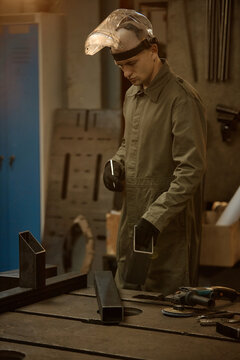 Young adult Caucasian male welder working with metal parts in workshop, representing industrial manufacturing and vocational training, vertical