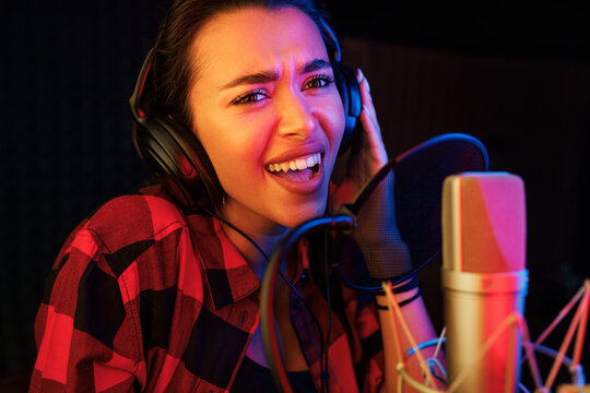 Close-up of young woman singing emotionally in a recording booth