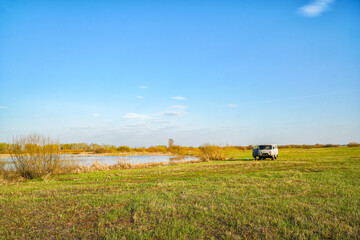Naklejka premium Old van parked in a green field near a lake