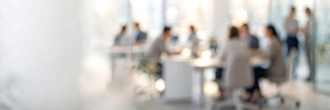 Softly blurred modern white corporate office interior with a diverse group of business professionals working naturally in the background. Bright open-plan workspace featuring clean white architecture.