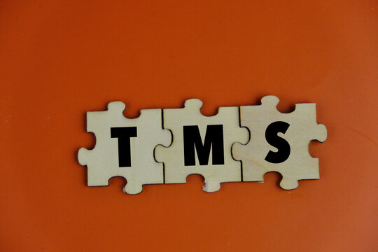 Transcranial Magnetic Stimulation TMS . text on wooden blocks. on an orange background