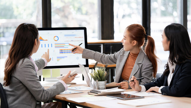 Asian Business Women Pointing at Computer Screen Analyzing Financial Charts in Office