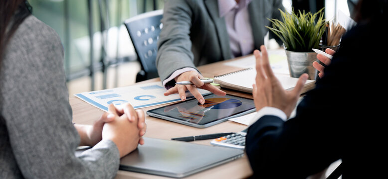 Close Up Business Team Pointing Finger and Pen at Tablet Displaying Charts in Office
