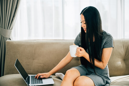 Young woman on comfy sofa enjoys remote education laptop coffee. Embracing learning relaxation in cozy living room. Modern education and comfort. Serene study setting.