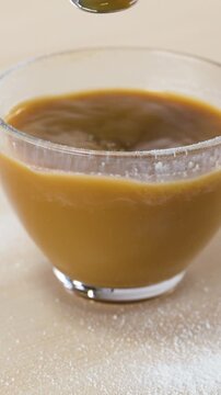 Stirring Hot Coffee with Dairy Alternative in a Clear Glass Mug