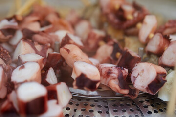 Close up of chopped boiled octopus or squid pieces on stainless steel steamer basket © mnimage