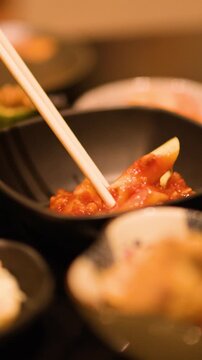 Person Using Chopsticks to Eat Pasta in Tomato Sauce