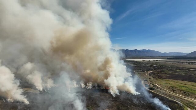 Flyover active grass wildfire producing tremendous thick smoke