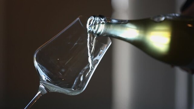 Sparkling white wine poured into tilted angular wine glass, close up