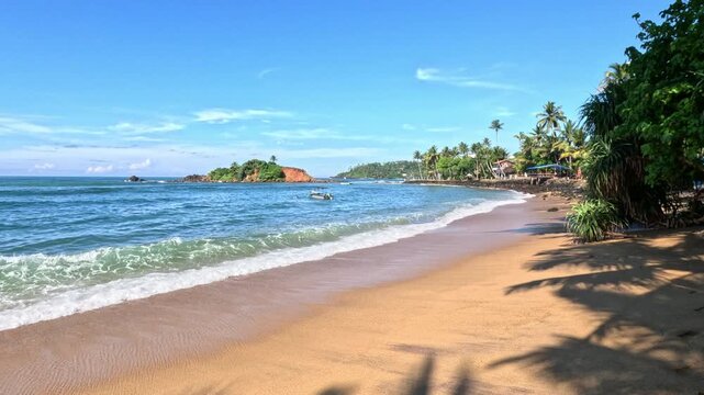 A wide view of a Sri Lanka beach on a bright sunny day featuring a prominent rock formation and a single boat floating near the shore.